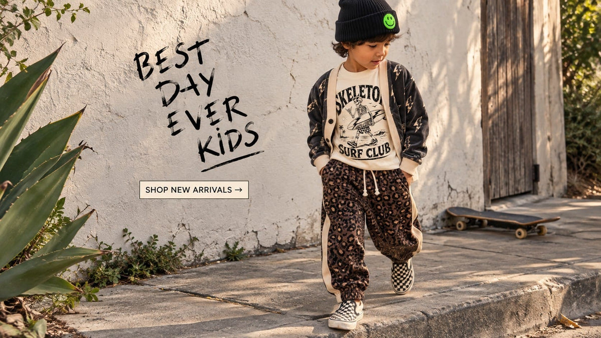 Boy in a smiley beanie, lightning-print cardigan and leopard joggers walking past a plaster wall