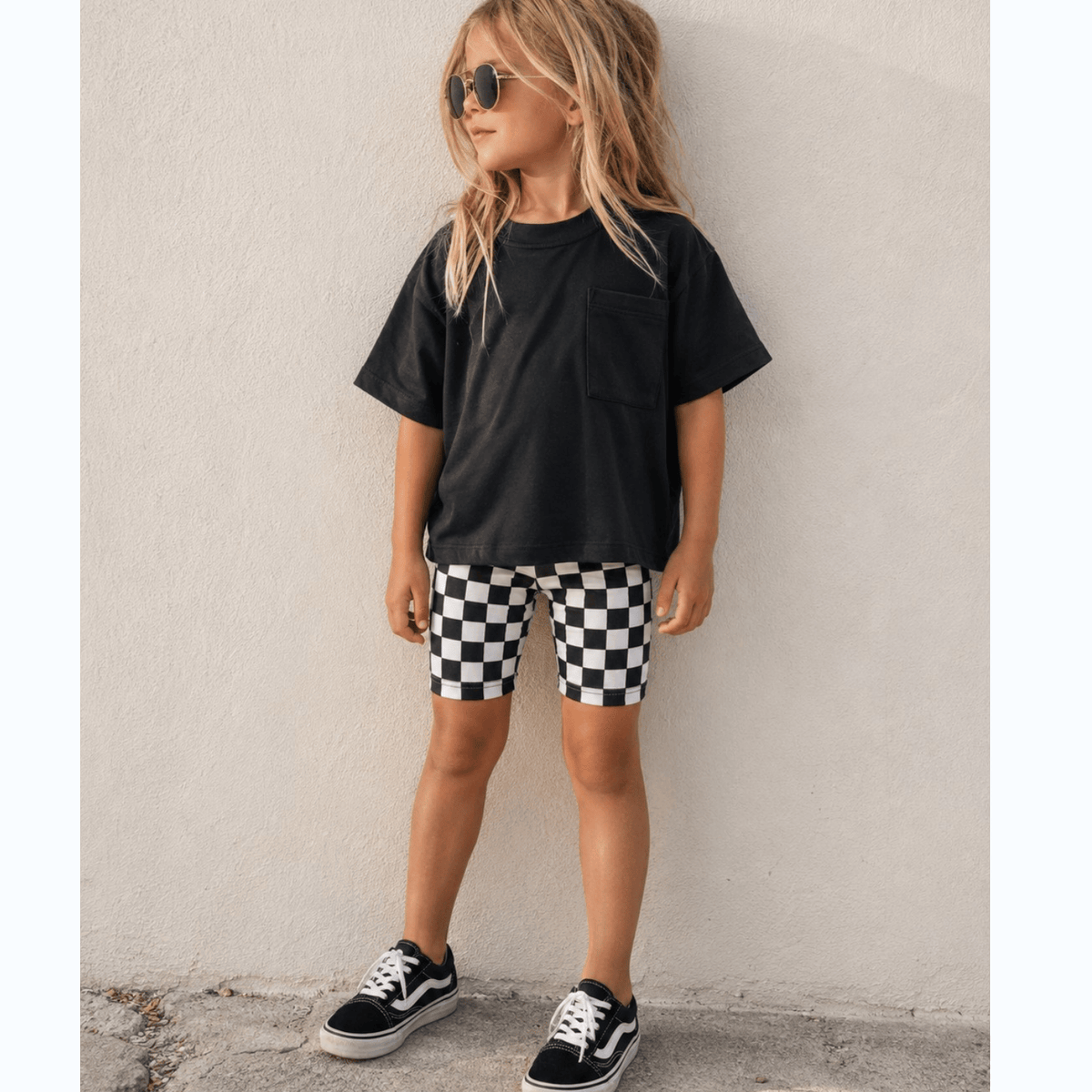 Kid in the black Hudson Oversized Pocket Tee with checkered biker shorts