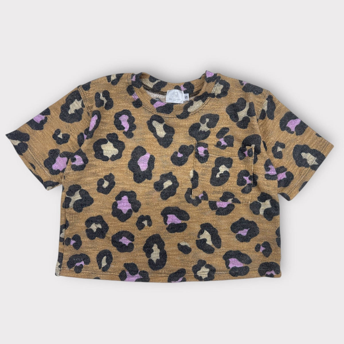 The Lazy Leopard Pocket Tee, tan with black and lilac leopard spots, laid flat