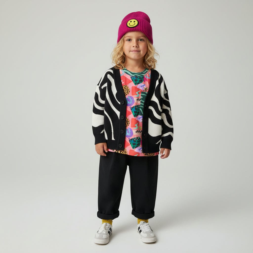 Kid in a pink beanie wearing the Trippy Tide Cardigan over a print tee with black pants