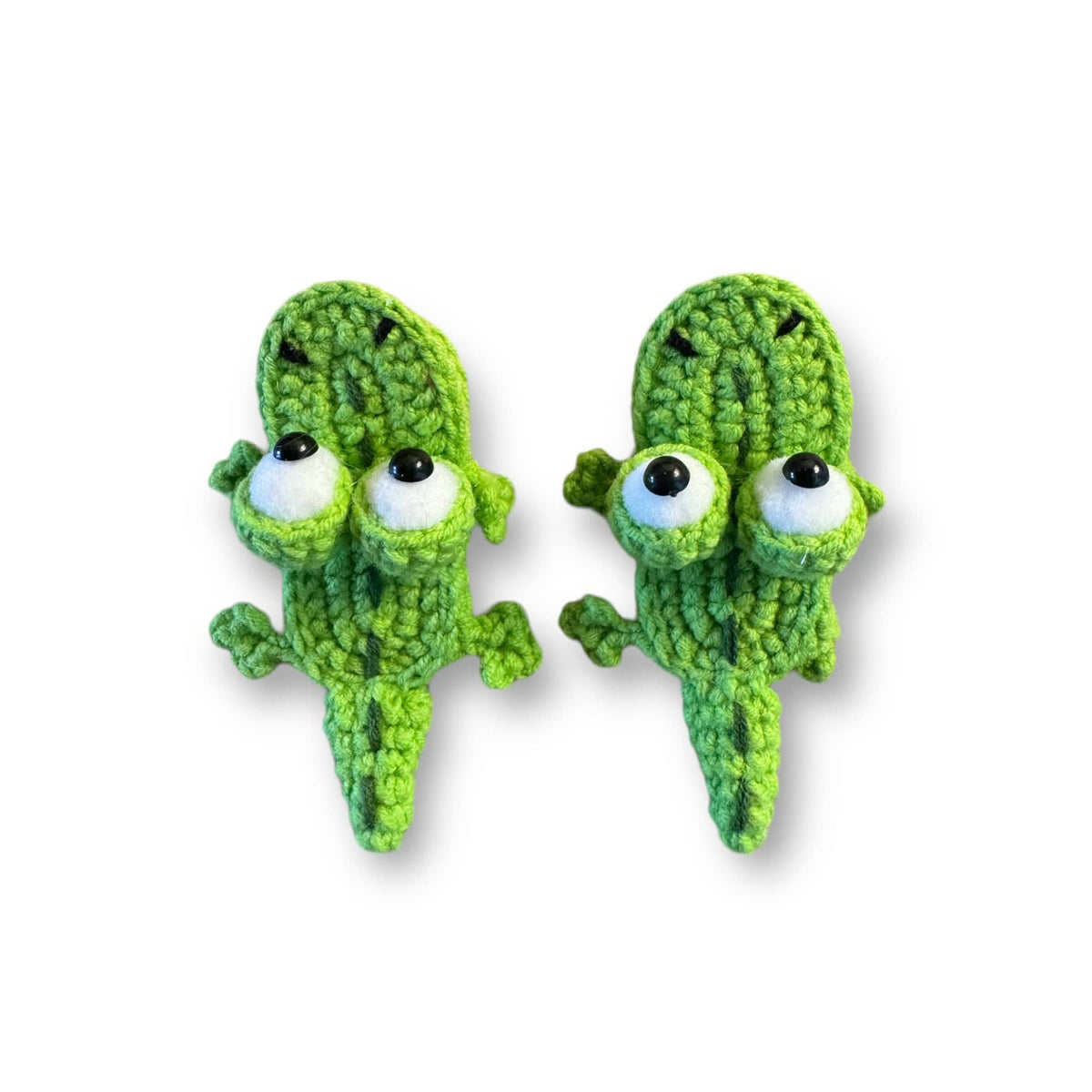 Two hand-crocheted green alligator hair clips with big eyes