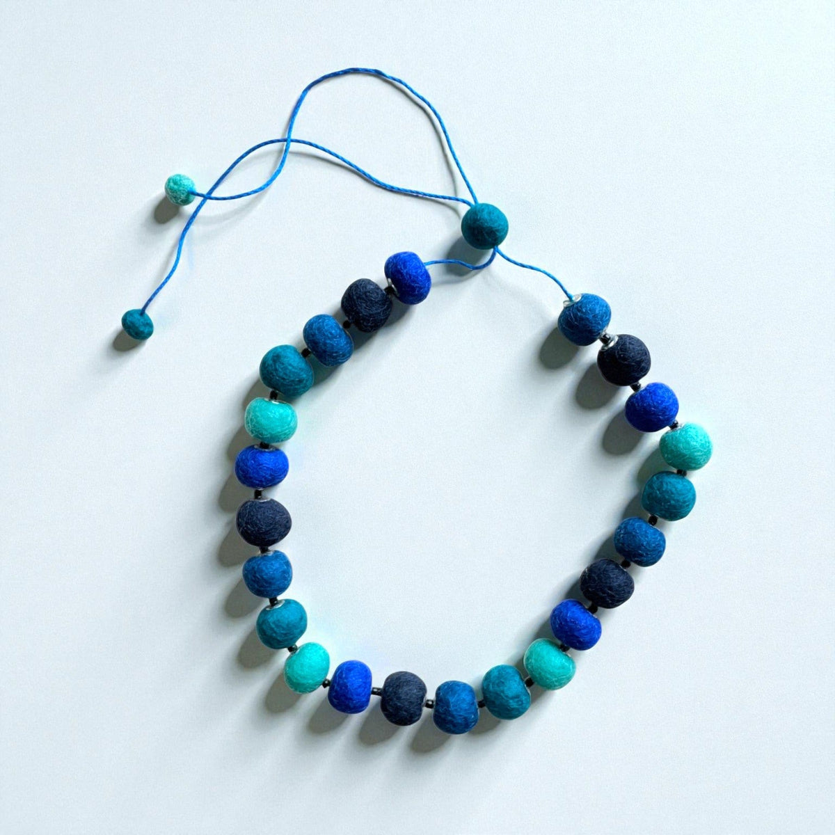 Felt bead necklace in shades of blue and teal