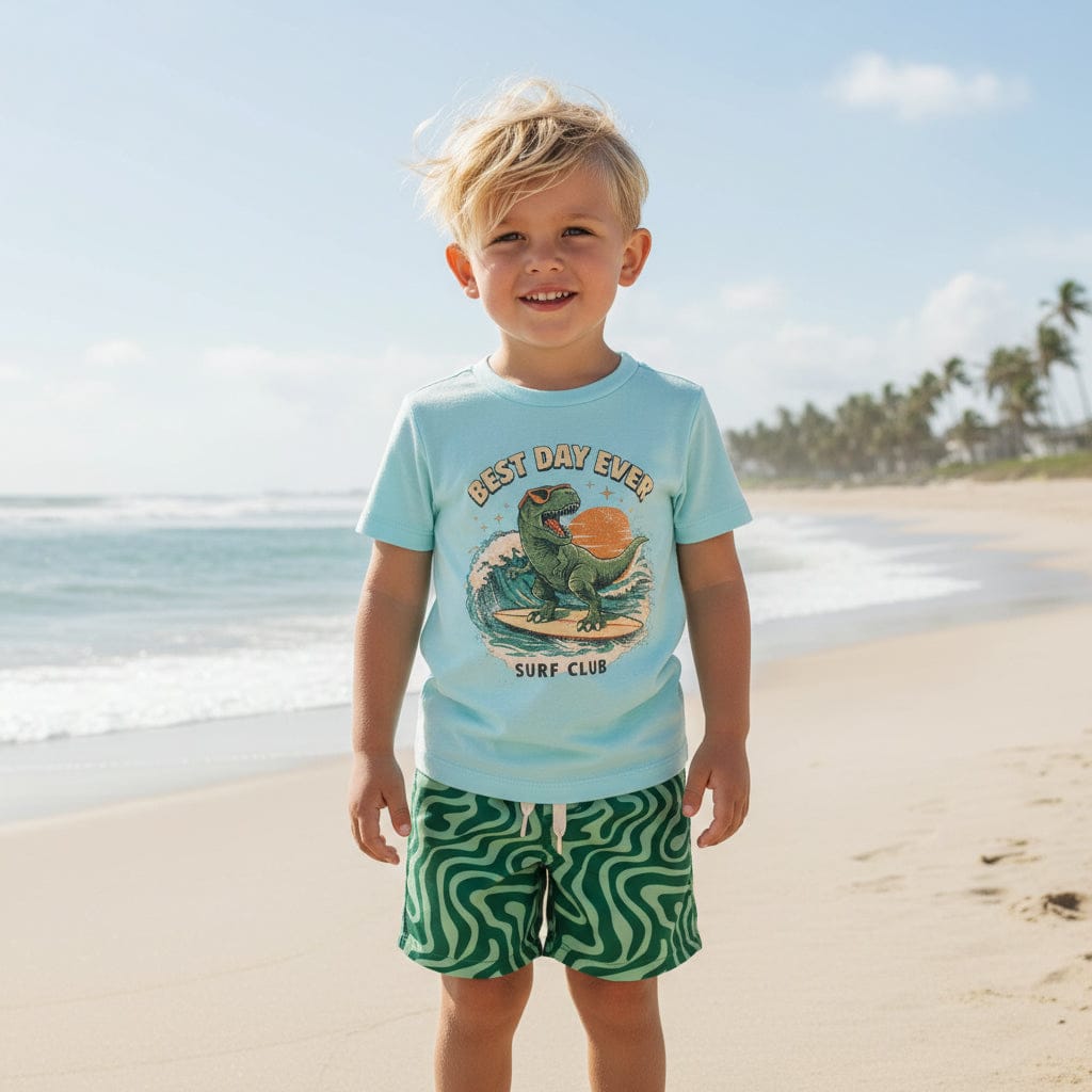 Kid on a beach in the Best Day Ever Surf Club tee and Trippy Tide Swim Trunks