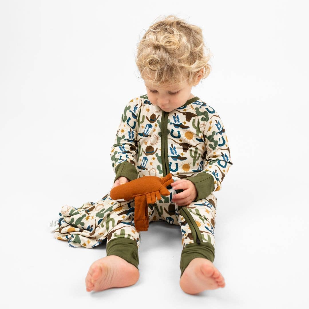 Toddler in western print pajamas holding the horse lovey
