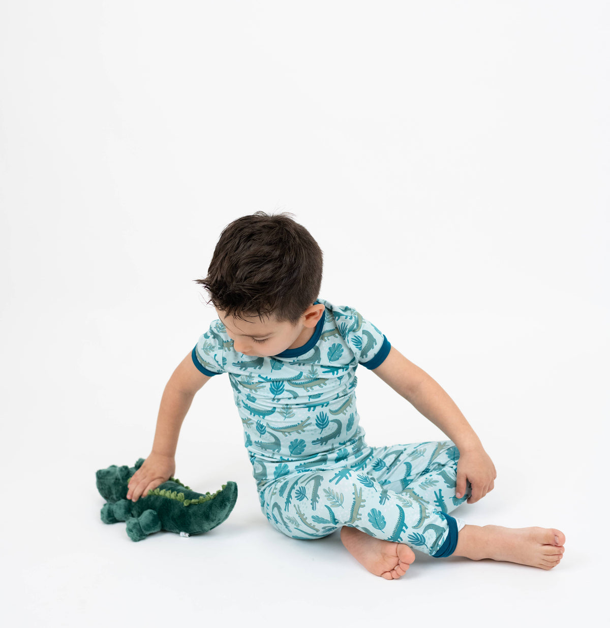 Boy in alligator print pajamas playing with Andy the alligator