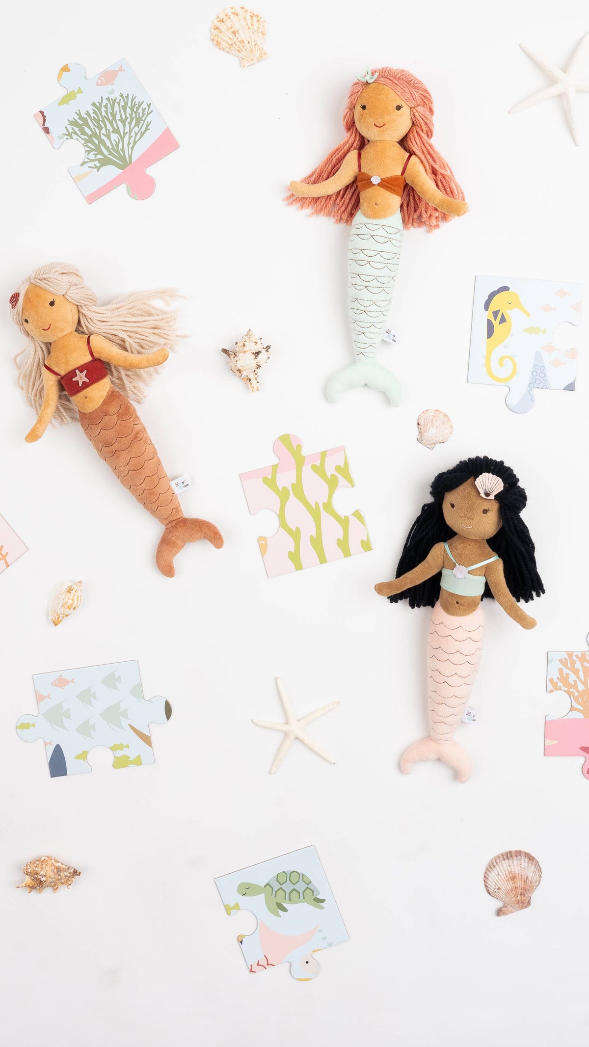 Mermaid plush dolls surrounded by shells and beach treasures