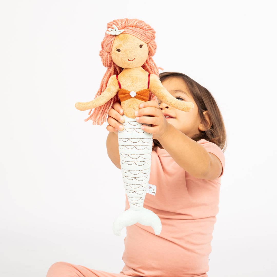 Girl in pink pajamas holding up Cordelia the Mermaid