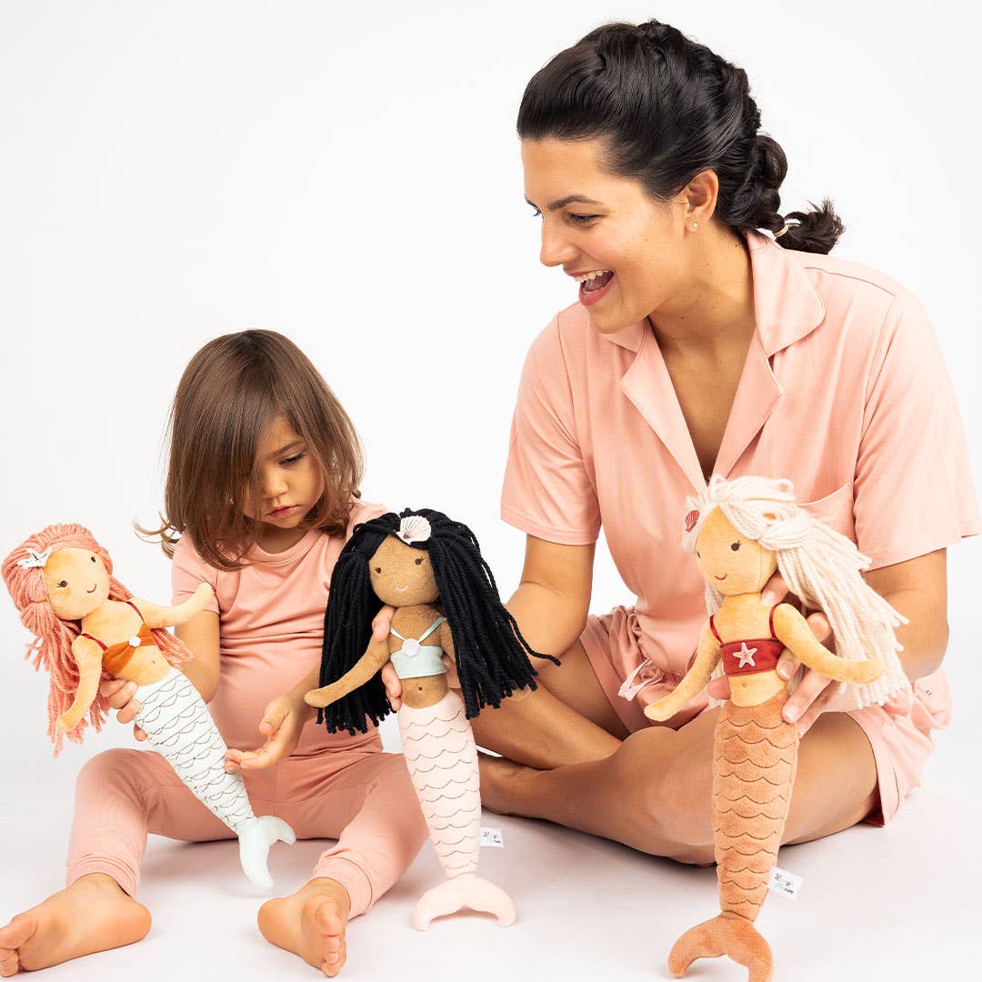 Mom and daughter playing with three mermaid plush dolls