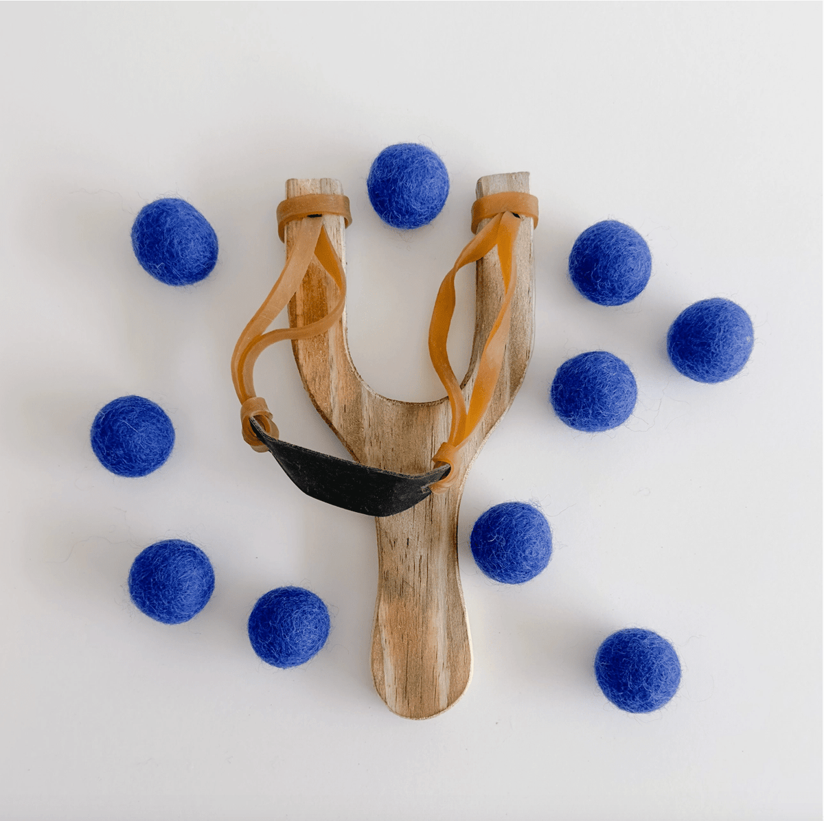 Wooden slingshot surrounded by navy felt balls