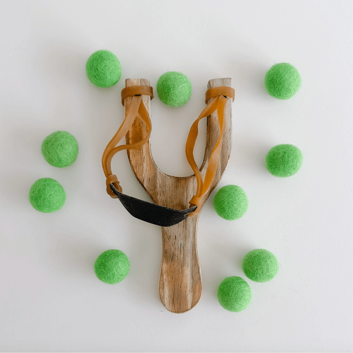 Wooden slingshot surrounded by green felt balls