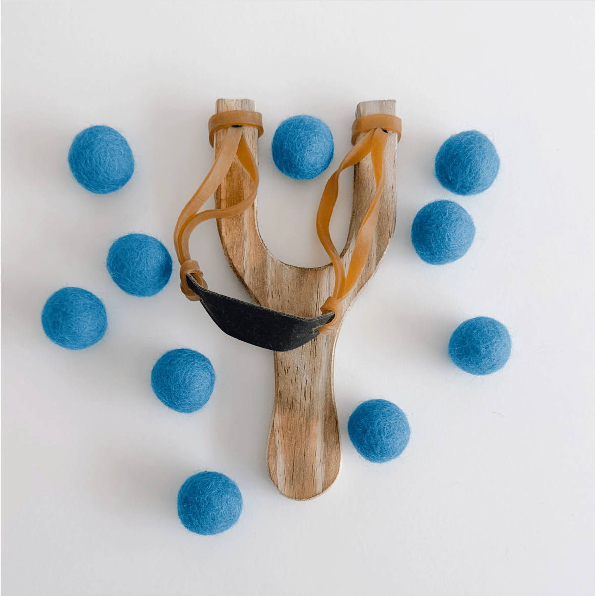 Wooden slingshot surrounded by light blue felt balls